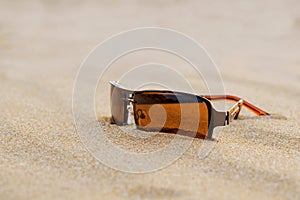 Brown sunglasses on sand on beach