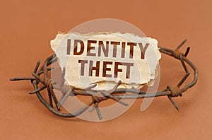 On a brown surface, barbed wire and a cardboard sign with the inscription - Identity theft