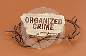 On a brown surface, barbed wire and a cardboard sign with the inscription - Organized Crime