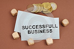 On a brown surface are coins, cubes and a business card with the inscription - Successfull Business