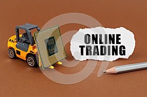 On a brown surface, a forklift is transporting a processor, next to it is paper with the inscription - Online trading