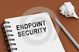 On a brown surface lies a pen, crumpled paper and a notepad with the inscription - ENDPOINT SECURITY