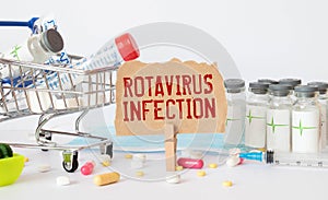 On a brown surface lies a stethoscope, pills and a notepad with the inscription - Rotavirus infection