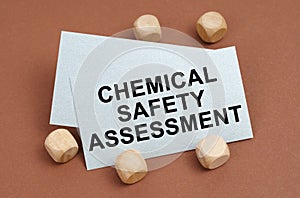 On a brown surface, wooden cubes and a business card with the inscription - Chemical Safety Assessment