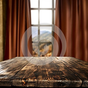 A brown table with blurred mountains and blue cloudy sky background behind the window.