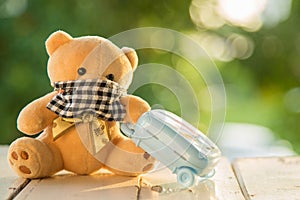 Brown teddy bear wearing a dust mask sitting on white wooden board with  pink luggage at side prepare to travel in vacation with