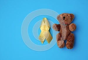 brown teddy bear and yellow silk ribbon on a blue background