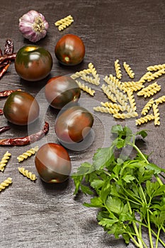 Brown tomatoes, parsley sprigs, spices and pasta. Top view.