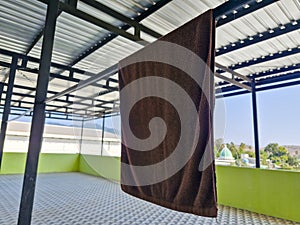 A brown towel drying under the sun on a rooftop