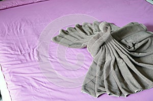 Brown towel plait as swan on pink bed