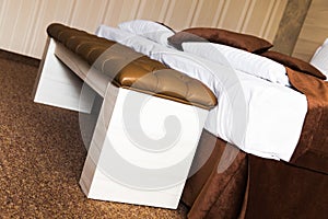 Brown upholstered leather footstool on a bed