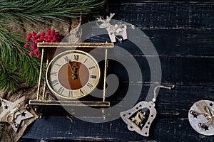 Brown vintage clock, pine branch and wooden reindeer toy on black background. Merry Christmas, Happy New Year eve, winter holidays
