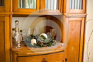 The brown vintage dressing table is decorated with a new year`s green tree branch, a white ball and a candle and crystal