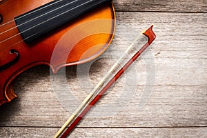 Brown violin with fiddle stick on wooden background. Art and mus