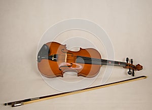 Brown violin with four strings and a violin bow