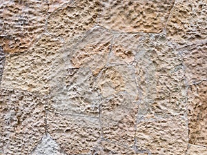 Brown wall of stone blocks of irregular shape and uneven surface for use as a background close up