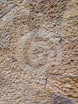 Brown wall of stone blocks of irregular shape and uneven surface for use as a background close up