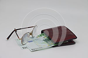 Brown wallet with banknotes and glasses. Brown frame. Symbol of accounting and family finance planning.