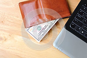 Brown wallet with Dollar cash and notebook on clean wood backgro