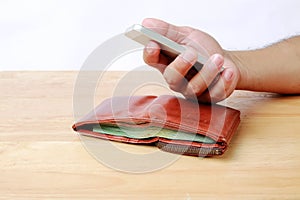 Brown wallet and Mobile phone in hand on wood background.