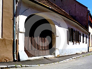 Brown weathered arched wooden gate and facade in old European town