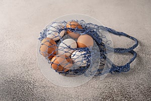 Brown and white chicken eggs in string bag on a light textured background. Copy space