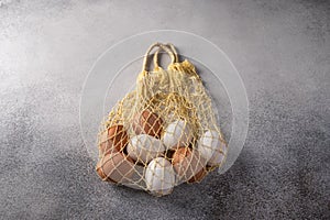 Brown and white chicken eggs in string bag on a light textured background. Copy space