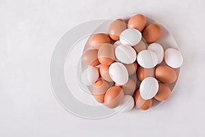 Brown and white eggs on a white plate on a white background. Eggs. Easter photo concept.