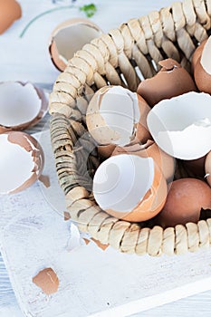 Brown and white eggshells placed in basket on white table, natural calcium source