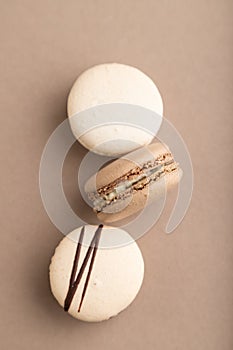 Brown and white macaroons on beige pastel background. top view, close up