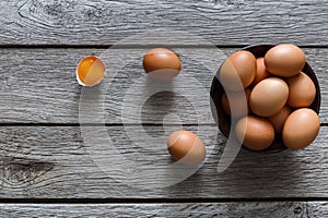 Brown and white organic eggs in bowl on wood background