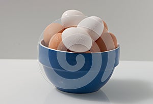 Brown and white wet eggs in a blue and white bowl