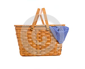 A brown wicker picnic basket on a white background with gingham cloth