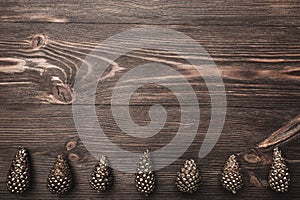 Brown wood background with pronounced texture. With golden cones at the bottom of the image.