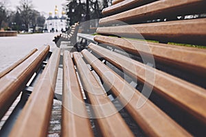 Brown wooden benches converge to the center pointing in the direction of a beautiful park