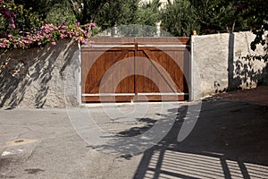 Brown wooden car close gate and a flowering wall