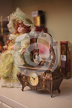 Brown wooden casket - clock on the shelf with a doll