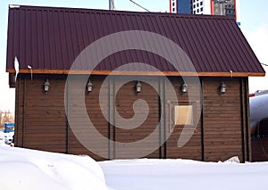 Brown wooden city house with balcony. Winter view