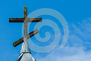 Brown wooden cross against blue sky