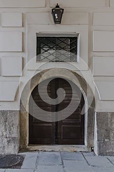 Brown wooden Elegant Double enterance door. Facade of baroque white building with stone panels