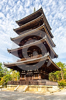 Brown wooden five-storied Buddhist pagoda with blue sky in autumn in Ninna-ji Temple Garden, Kyoto, Japan.