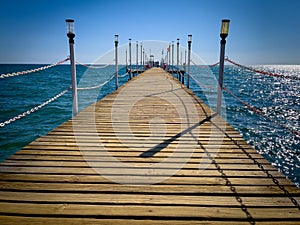 Brown wooden jetty leads to the baller sea