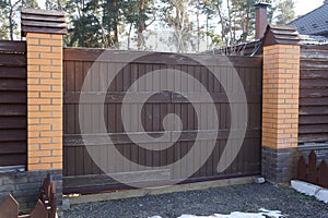 brown wooden plank gate and part of a brick fence in the street