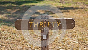 Brown wooden sign in grassy field with thrifty written on it photo