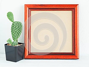Brown wooden square photo frame and cactus on the wooden shel.