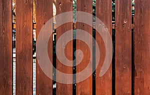 Brown wooden vertical plank fence with sun glare