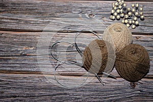 brown yarn on wooden textured background and two crochet.needle