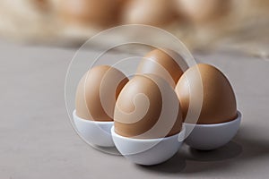 Brown or yellow Fresh farm eggs on quaternary eggcup, eggs background