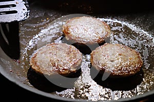 Browned sausage patties frying in frying pan