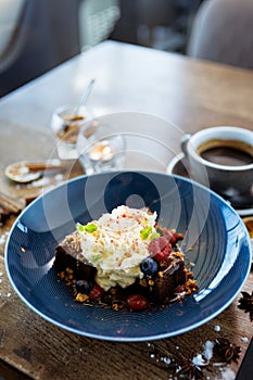 Brownie cake with salted caramel. Anglaise foam, raspberry sauce, praline nut and fresh berry. Delicious sweet dessert